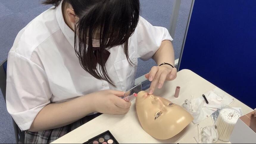 生徒がマネキン人形にメイクをしている様子