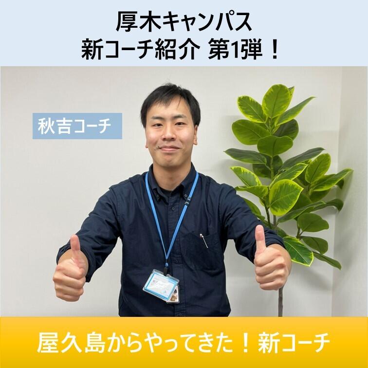 秋吉コーチが緑の前で両手でグッドをしている写真