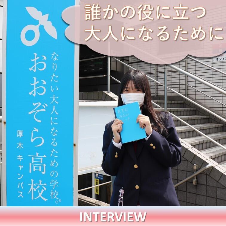 彩空さんが厚木キャンパスの前でKTCみらいノート®を持っている写真