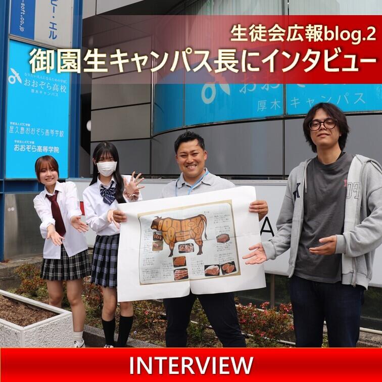 御園生キャンパス長と生徒会広報の生徒がキャンパスの前で並んでいる写真