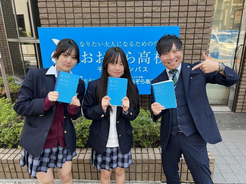 生徒と成人男性がノートをもってポーズを決めている