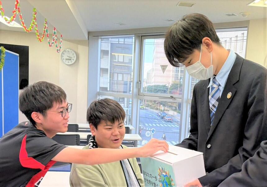 男子生徒が募金活動していて、お金を入れている様子