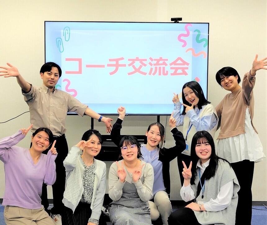 コーチ男女8人がTV画面前にてポースを取っている様子