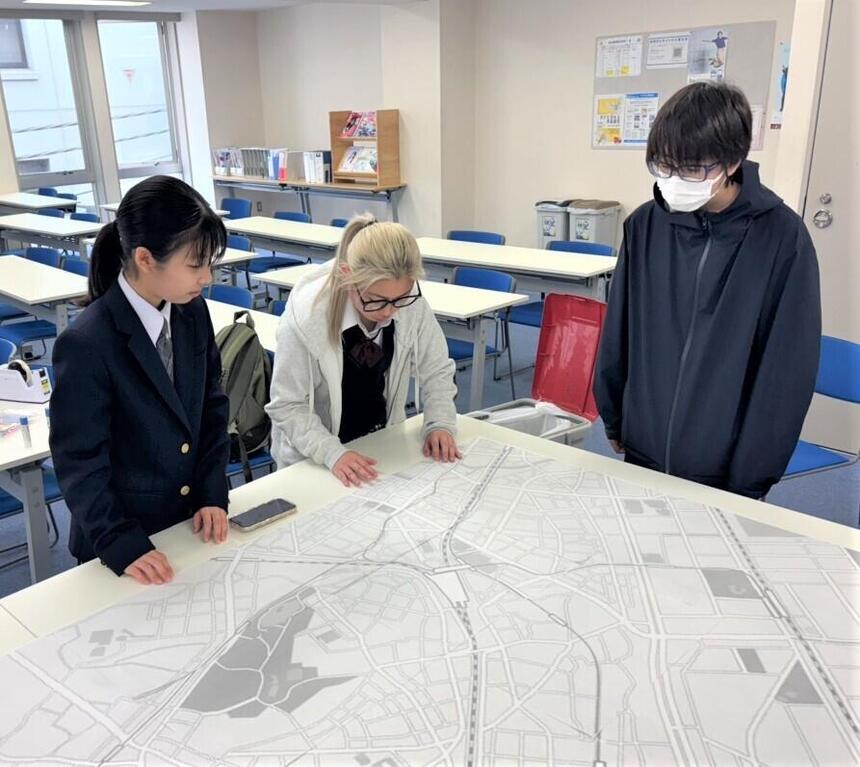 大きな千葉駅付近の地図を広げ、生徒3人が集っている様子