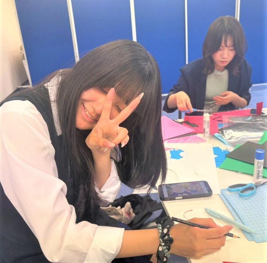 女子生徒がお祭り準備の作業をしながらポーズを取っている様子