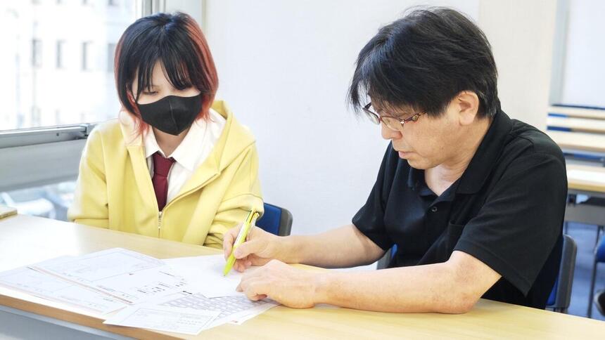 男性講師と女子高校生がマンガのアドバイスをしてもらっている様子