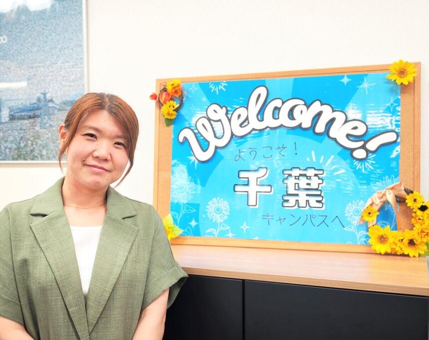 女性職員がウェルカムボード前でポーズを取っている様子