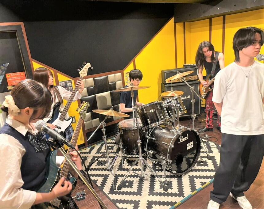 男女混成5名のバンドがスタジオで練習をしている様子