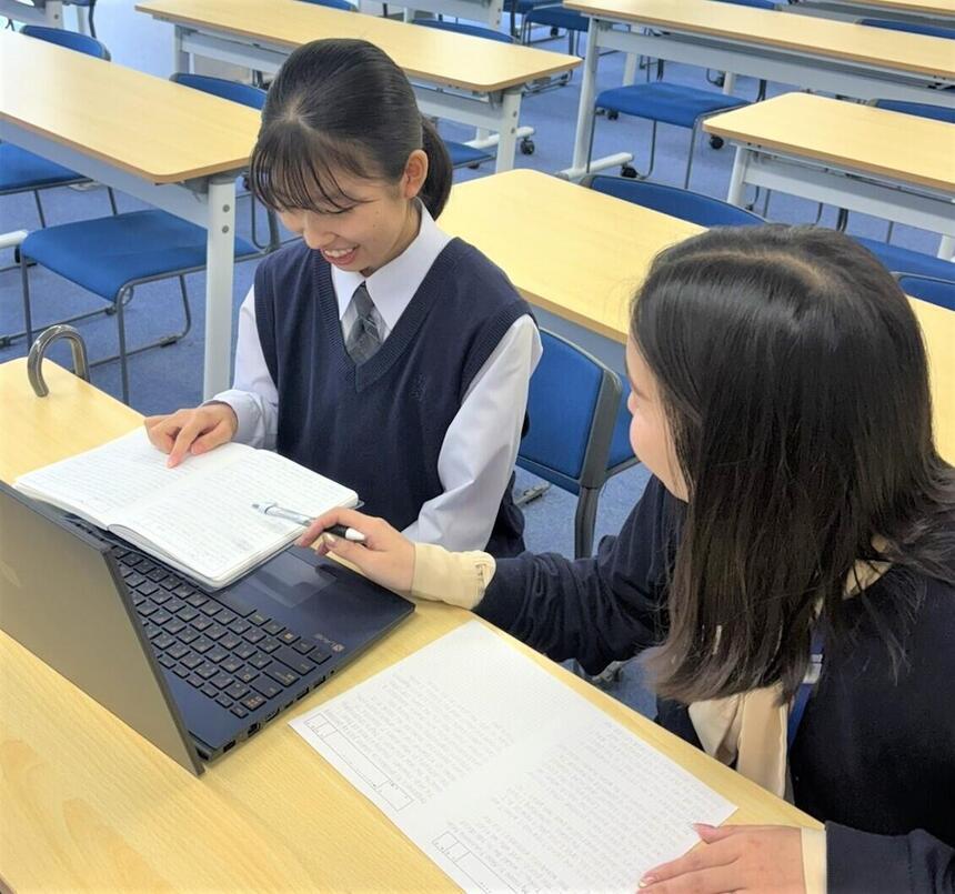 担当する女性コーチと女子生徒が一緒に英作文を作成している様子