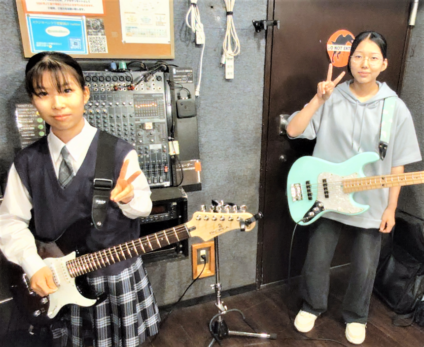 楽器を持った女子高校生2名がポーズを取っている様子