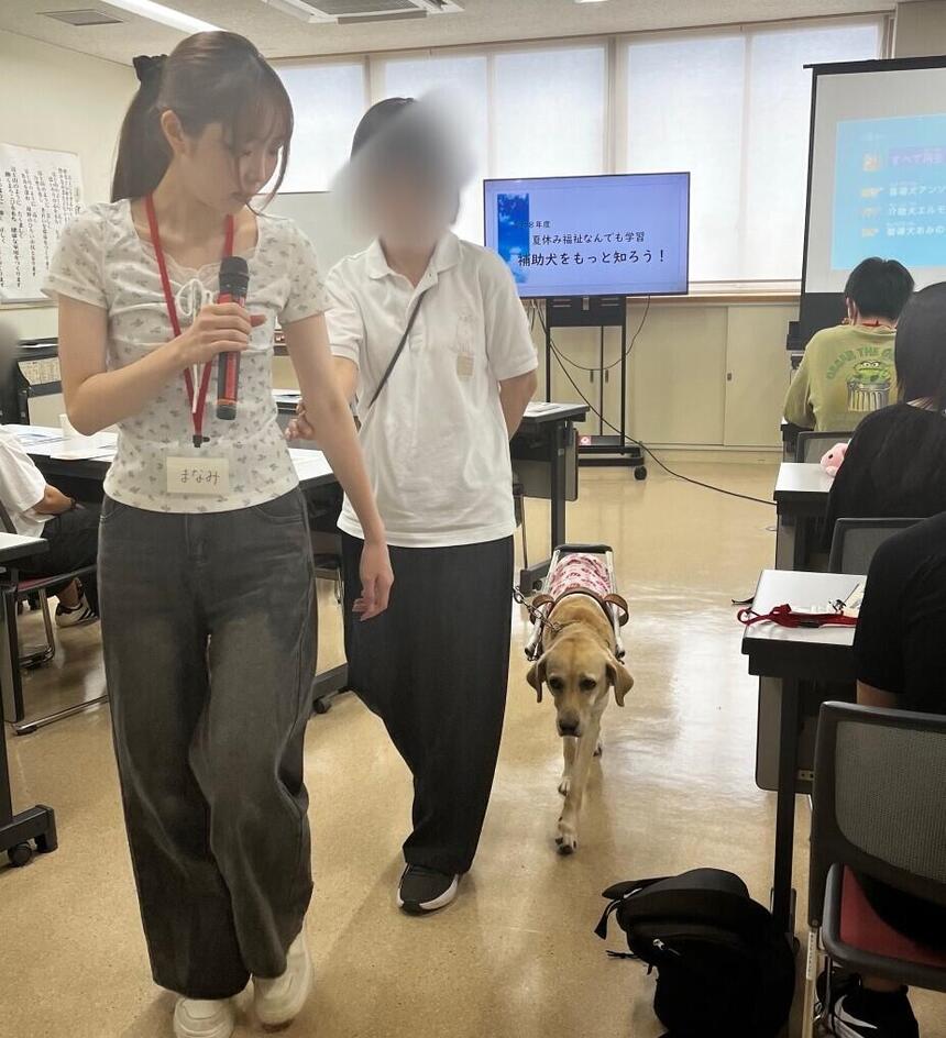 夏休み中、ボランティア活動で盲導犬の誘導を実践する生徒