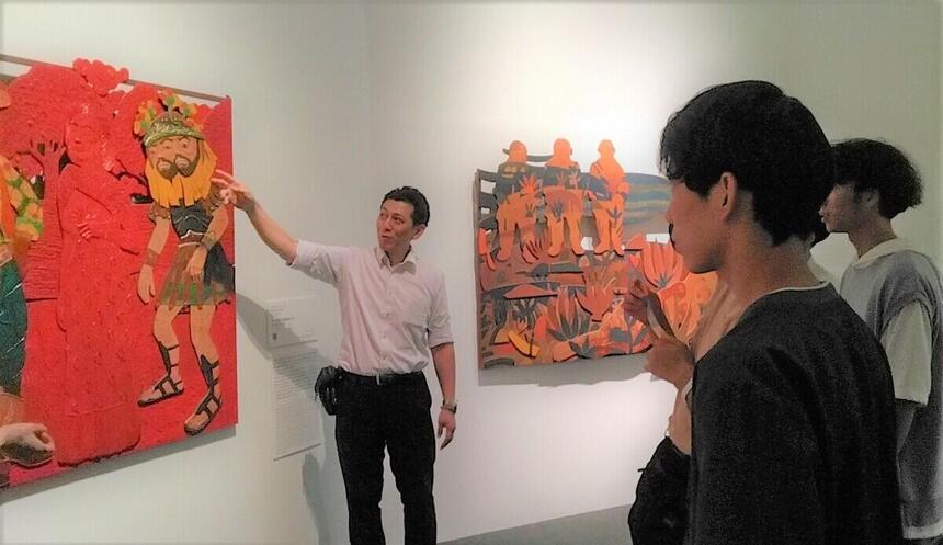 作品を鑑賞する生徒と解説する男性