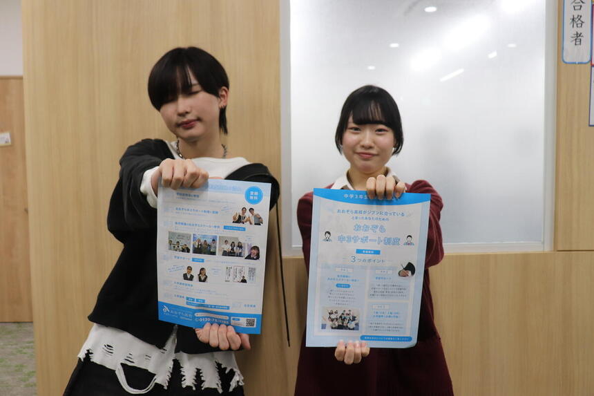 2人の男女がチラシを胸の前で持って笑顔でにっこりしている写真。