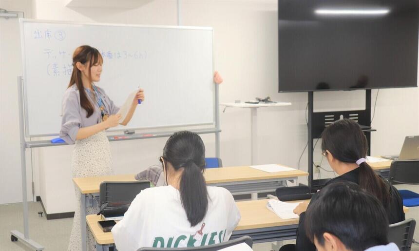 生徒がコーチから教室で問題について説明を受けている様子