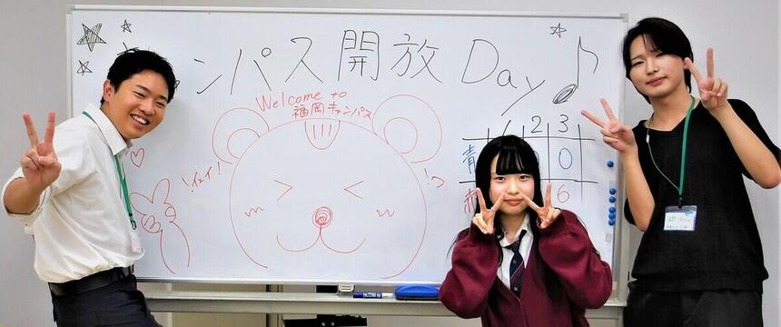 キャンパス開放Dayにておおぞらアンバサダーの3名がウェルカムボードの前で体験に来られた中学生を迎えている様子