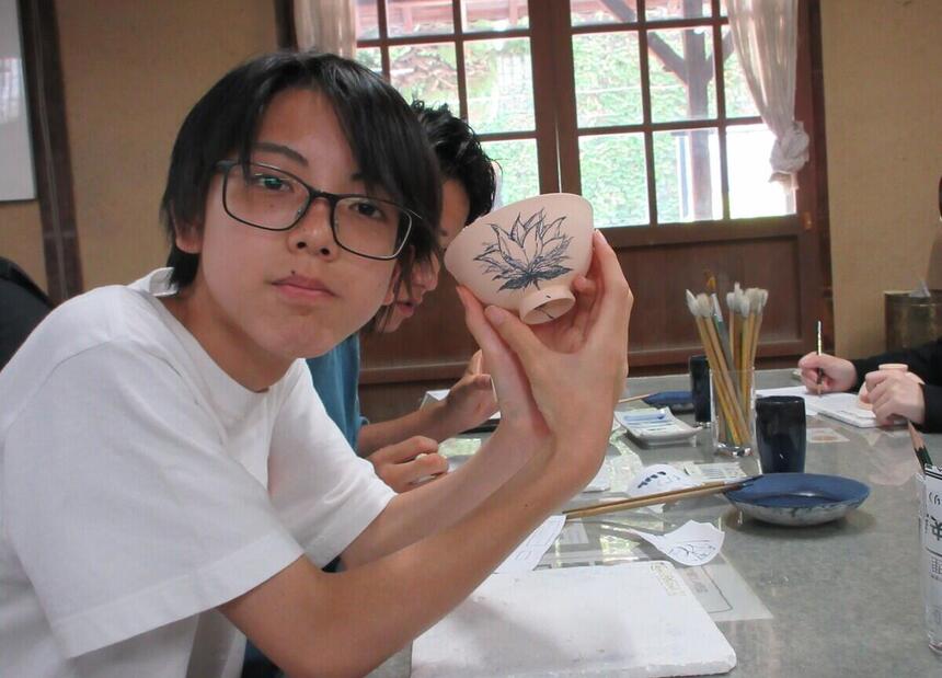 7月末に倉敷の陶芸工房で参加生徒が絵付けをした茶碗をもっている写真