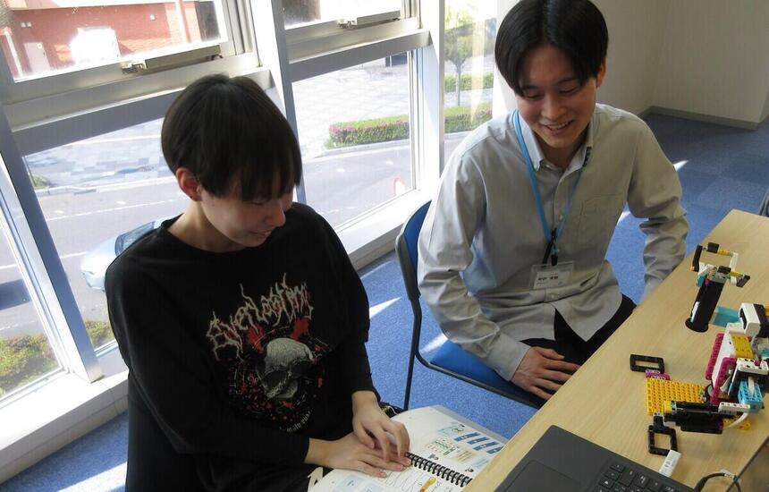 教室でプログラミングコース中の生徒がわからない部分をコーチに教わっている様子