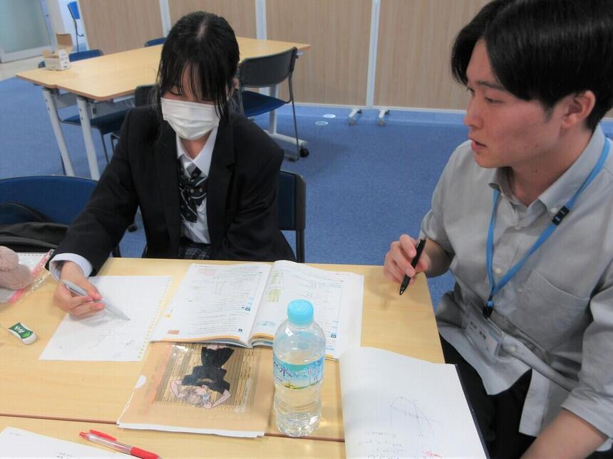 進学コースの時間にコーチからわからないところを生徒に教えてもらっている様子
