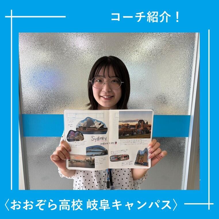 岐阜キャンパスの教室で、スタッフがノートを見せて笑っている様子