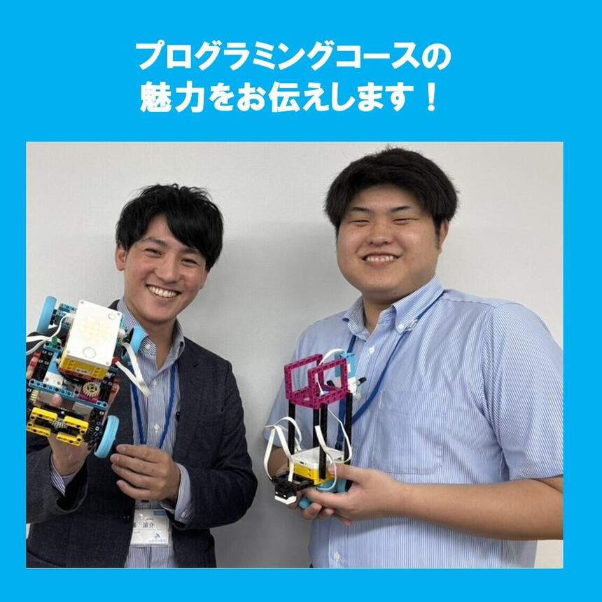 プログラミングコース担当のコーチ二人が生徒が作成したロボットを持って微笑んでいる様子