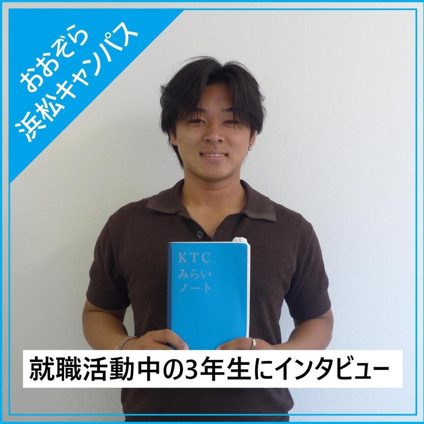 白い壁の前でインタビューを受けた男子生徒が自分のKTCみらいノート®を持っている写真。