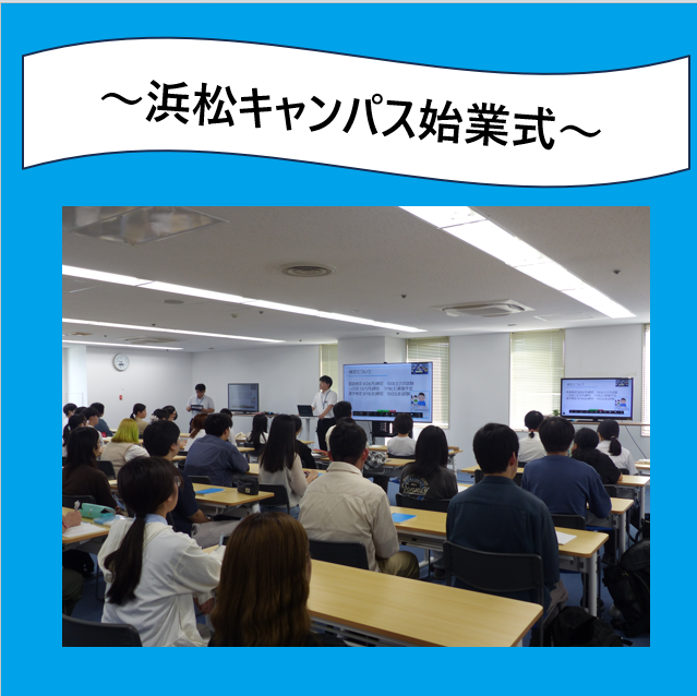 始業式の時間に液晶画面の前に男性スタッフが立ち、スライドを使って話をしている。その話を椅子に座り聞いている大勢の生徒の様子。