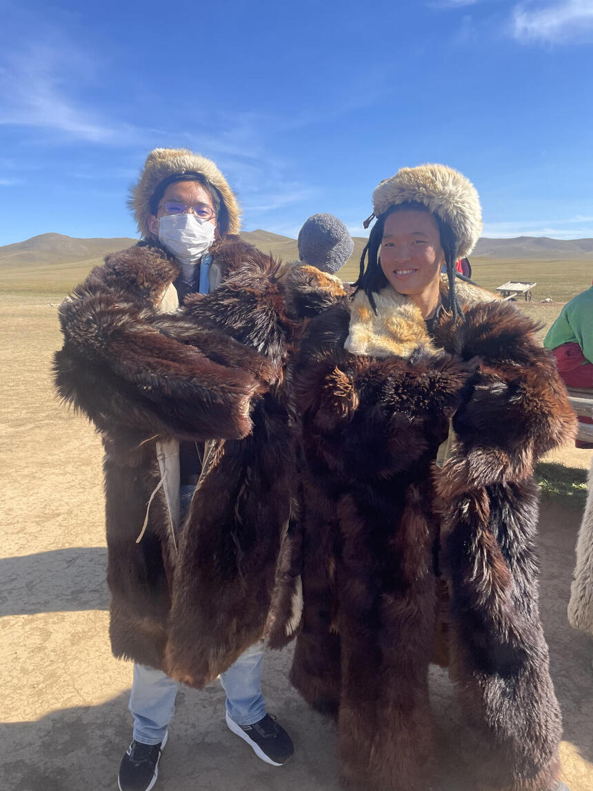 モンゴルの砂漠でモンゴルの民族衣装を着てポーズを決めている男子生徒二人