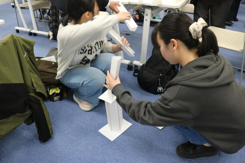 キャンパス内での新入生歓迎会にて、レクリエーションのひとつ「ペーパータワー」を作っている生徒の様子