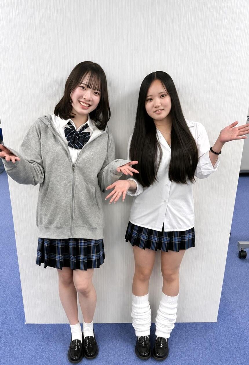 教室で制服を着た女子生徒2名が手を広げて笑って立っている写真
