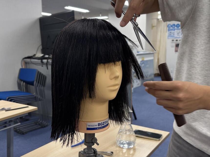 アルファジャパン美容専門学校出張授業でのマネキンを用いたヘアカットを生徒が行っている様子