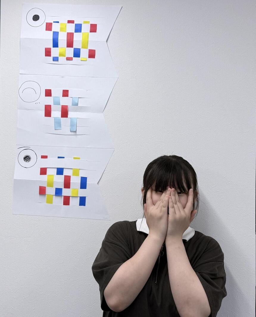 壁側に立ち、ポーズを決めている生徒の写真