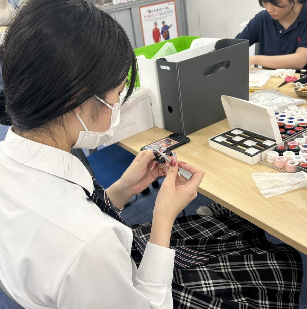ネイル道具一式を机の上のうえに広げてマグネットネイルに挑戦する女子生徒2人組