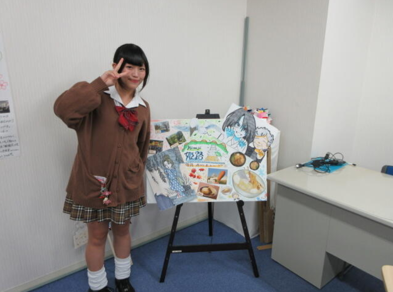 姫路キャンパス掲示物の前でピースで写真に写るインタビューに協力してくれた女子生徒