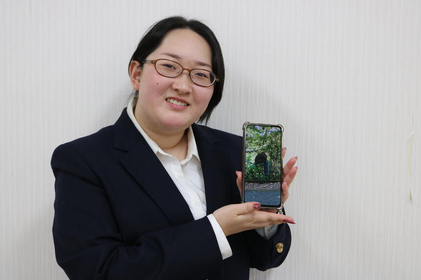 女子生徒がヤクザルの写真とともに笑顔で写っている様子