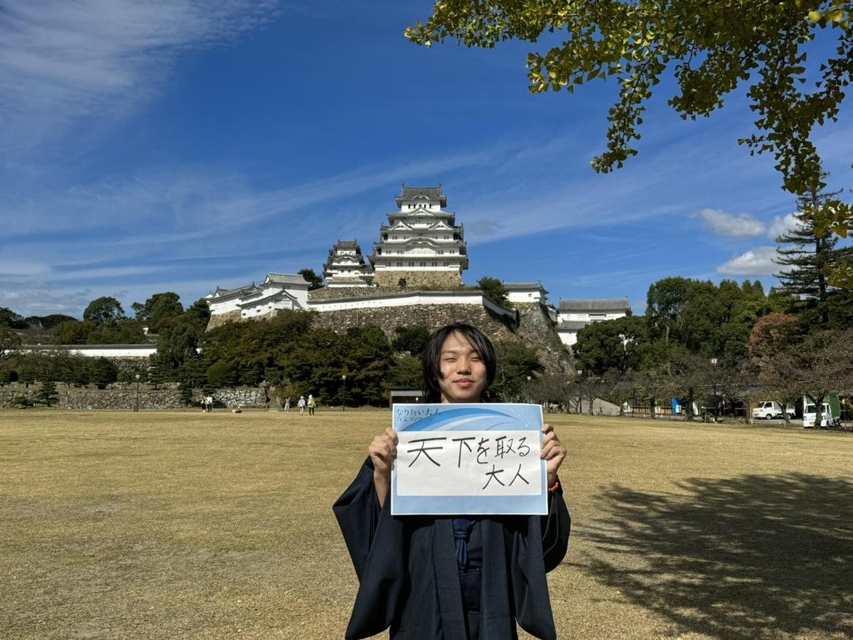 姫路城前でなりたい大人作文コンクール「天下を取る大人」を持って撮影したベストショットのレツさん