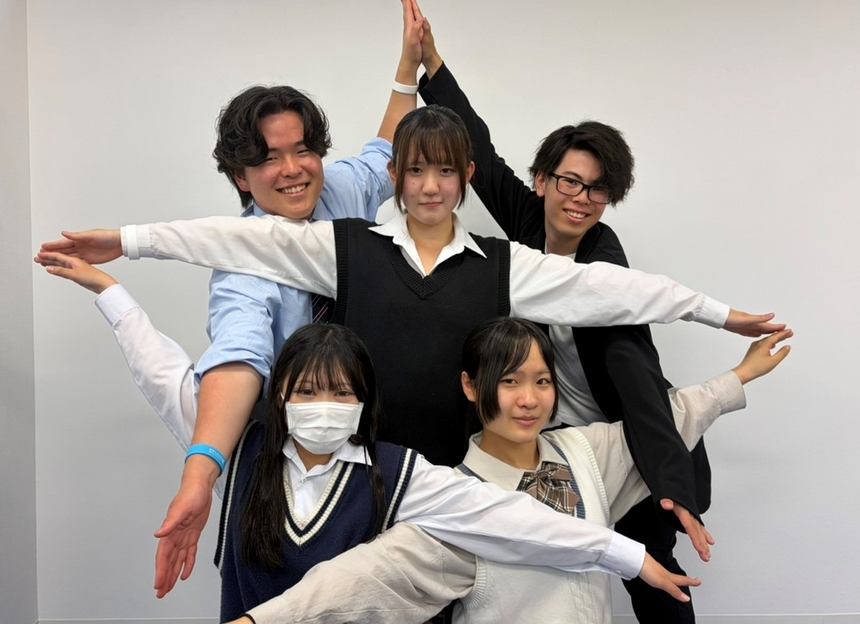 キャンパスの教室でインタビューを受けた生徒たちが仲良くポーズを取っている様子