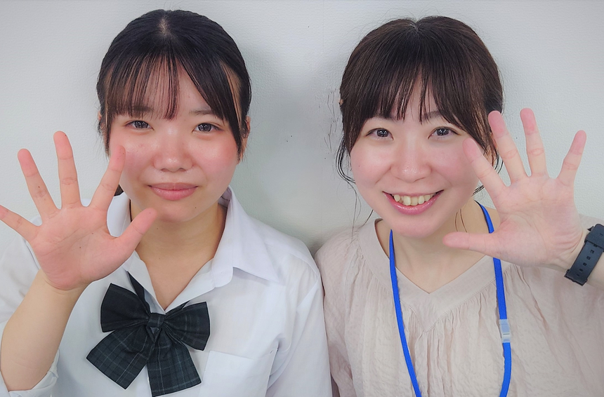 キャンパスの教室で生徒とコーチが笑顔で楽しそうにポーズをとっている様子