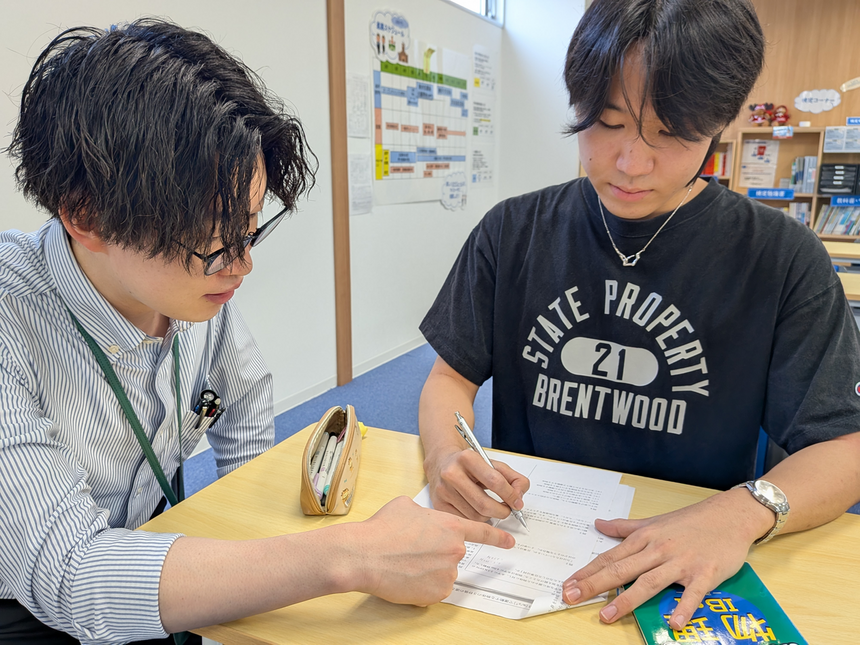 教室で模試の振り返りをする生徒とサポートするコーチの様子