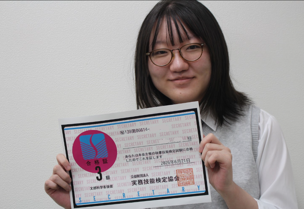 秘書検定の合格通知を手に、喜んでいる生徒の様子