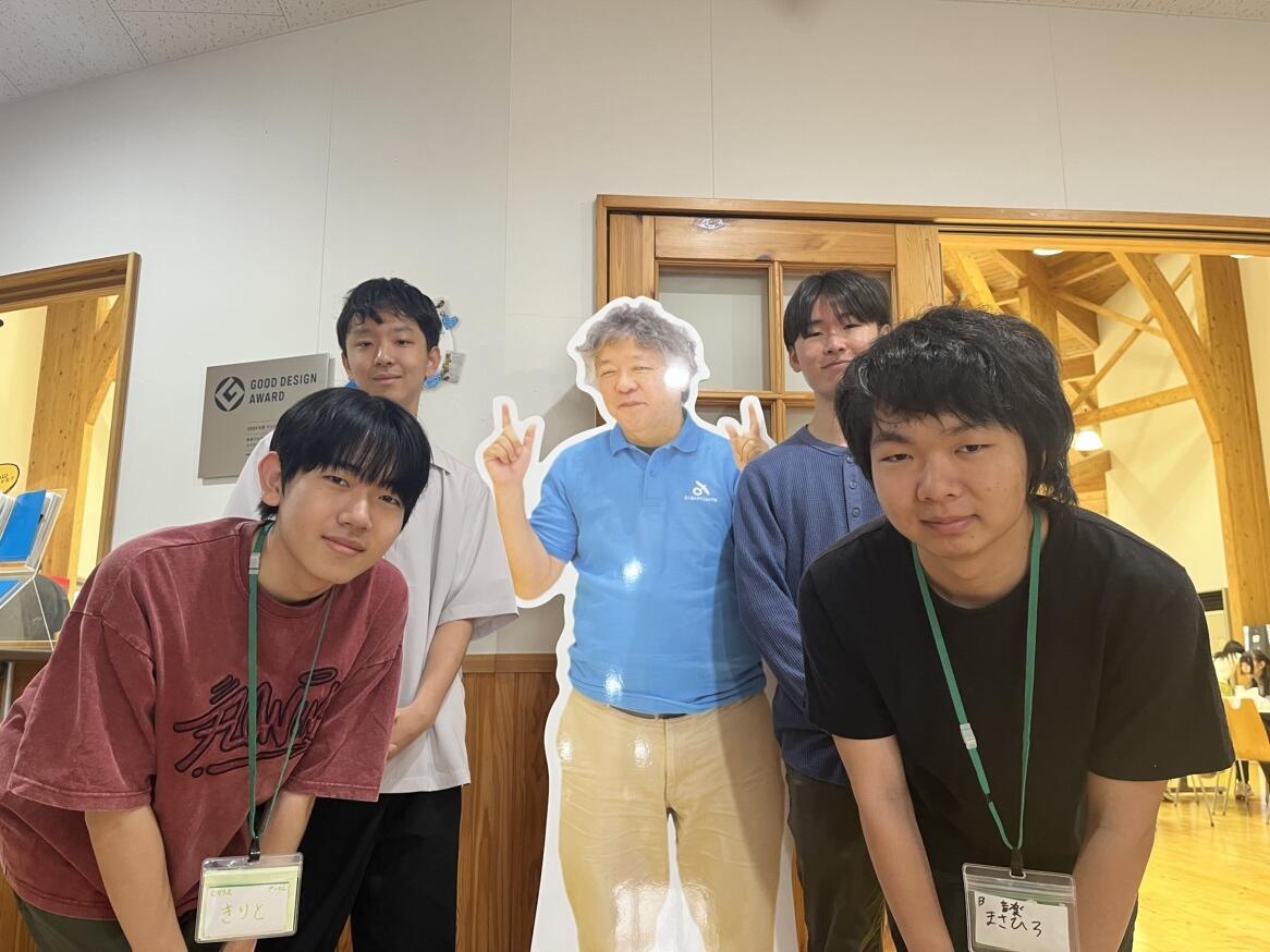 屋久島スクーリング時に屋久島おおぞら高等学校校長の茂木健一郎校長等身大パネルの前で集合写真を撮った3年次男子生徒