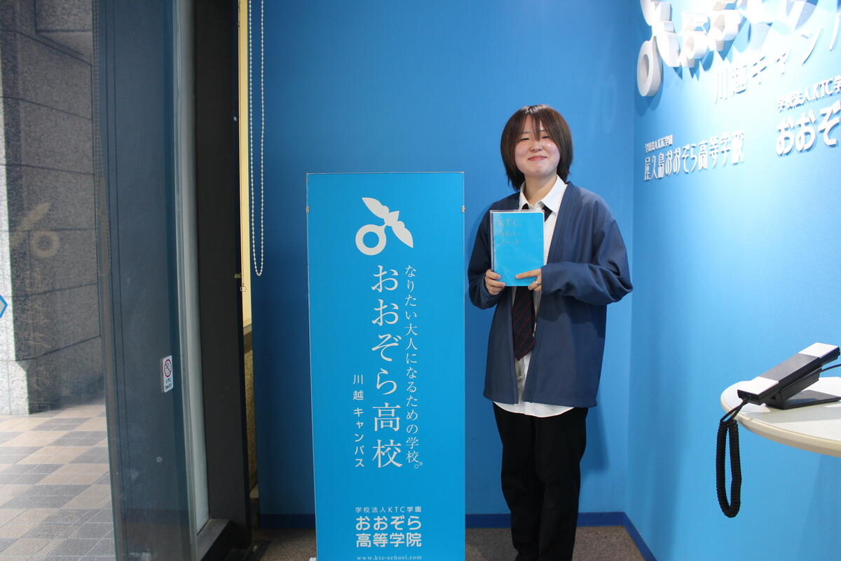 留学から帰ってきた生徒にインタビューの際、キャンパスの入口でKTCみらいノート®を手に写真を撮りました