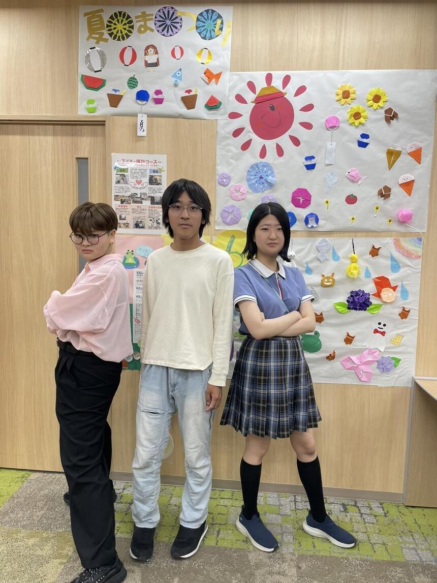 女子生徒2人と男子生徒1人が自分で作成した制作物の前でかっこいいポーズをしている写真