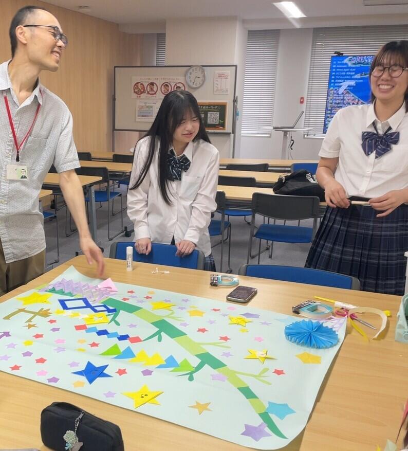 女子生徒2人と男性のコーチ1人が子ども・福祉コースの授業で制作物を作成している写真