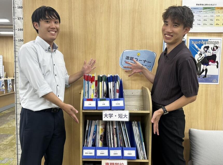 男性コーチ2名が新しく作られた進路コーナーを目立たせて紹介する様子