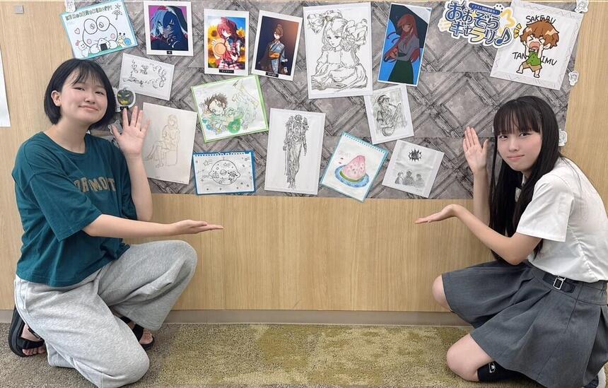 3年生の生徒2名がイラスト掲示ブースを囲んで紹介をしている様子。
