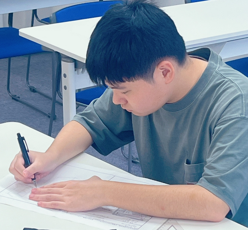 男子高校生が定規を用いて、直線を引いてデザインしている様子。