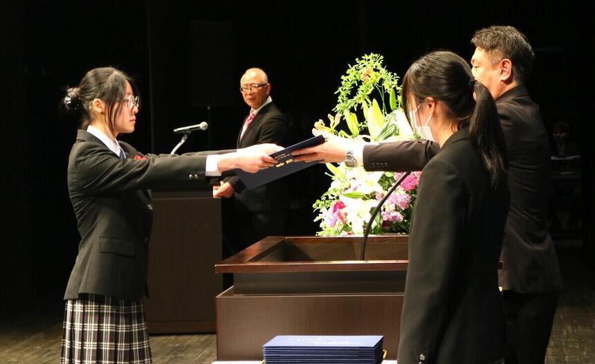 卒業証書を渡すコーチと受け取る生徒