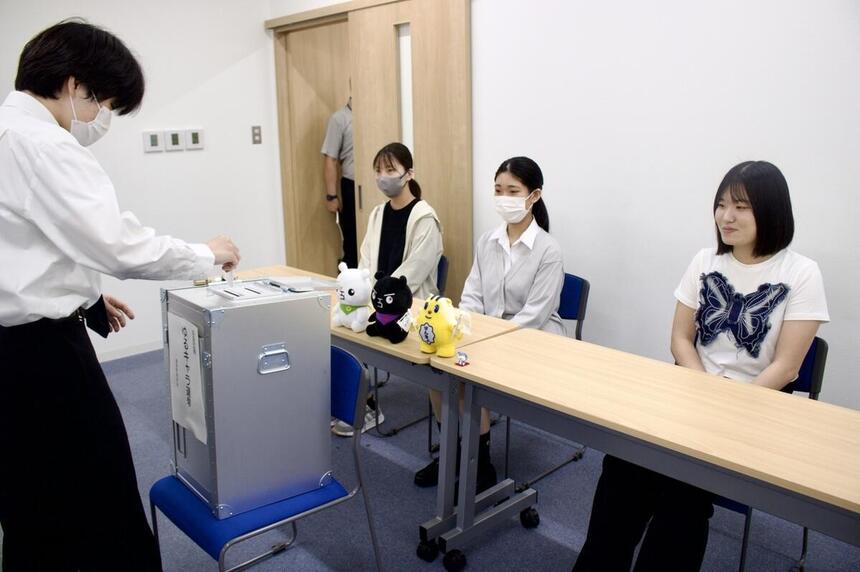 模擬投票を行うため、特別授業中に生徒が実際の投票箱に用紙を入れる様子