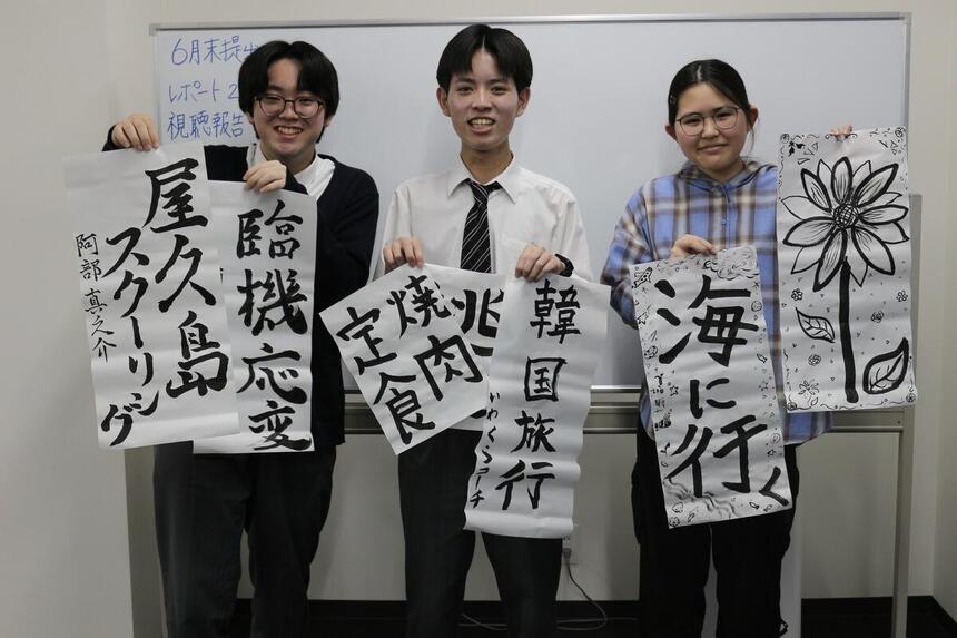 夏休みにしたいことを書いた半紙をもつ3人の生徒