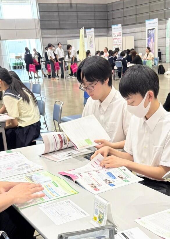外部の進路イベントに行き、学校ブースにて話を聞いている生徒の写真です。